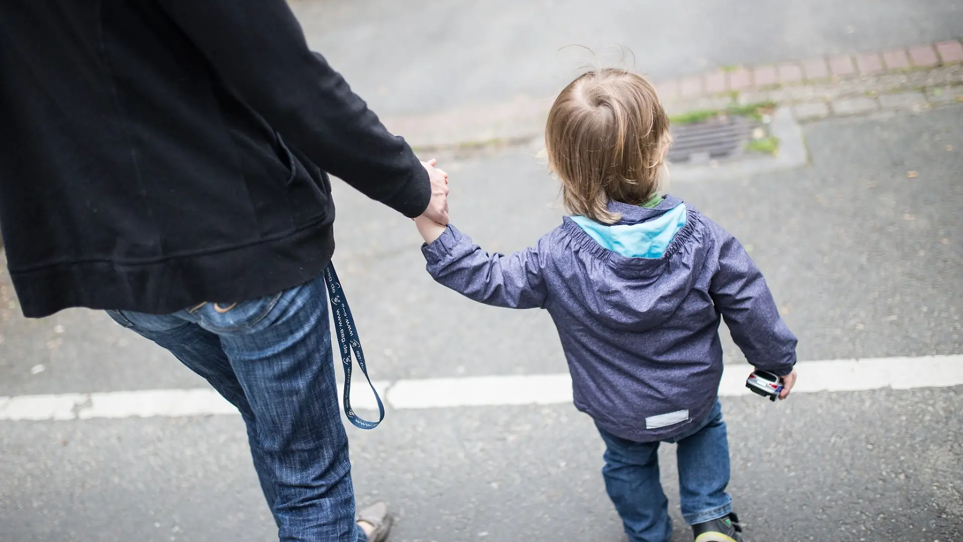 Eine Mutter hält ihren Sohn an der Hand.