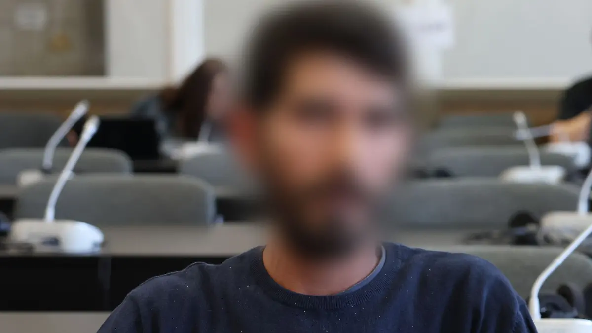 Der Angeklagte sitzt kurz vor Beginn der Verhandlung in einem Gerichtssaal.