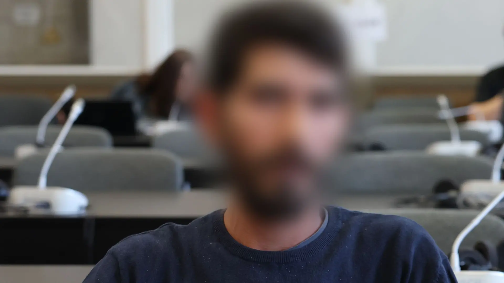 Der Angeklagte sitzt kurz vor Beginn der Verhandlung in einem Gerichtssaal.