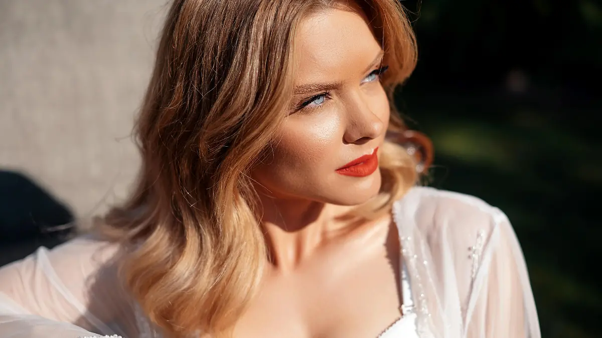 Portrait of attractive young woman with blue eyes and blond hair posing on nature. Stunning bride having wedding makeup and hairstyle. Concept of people, event and celebration.