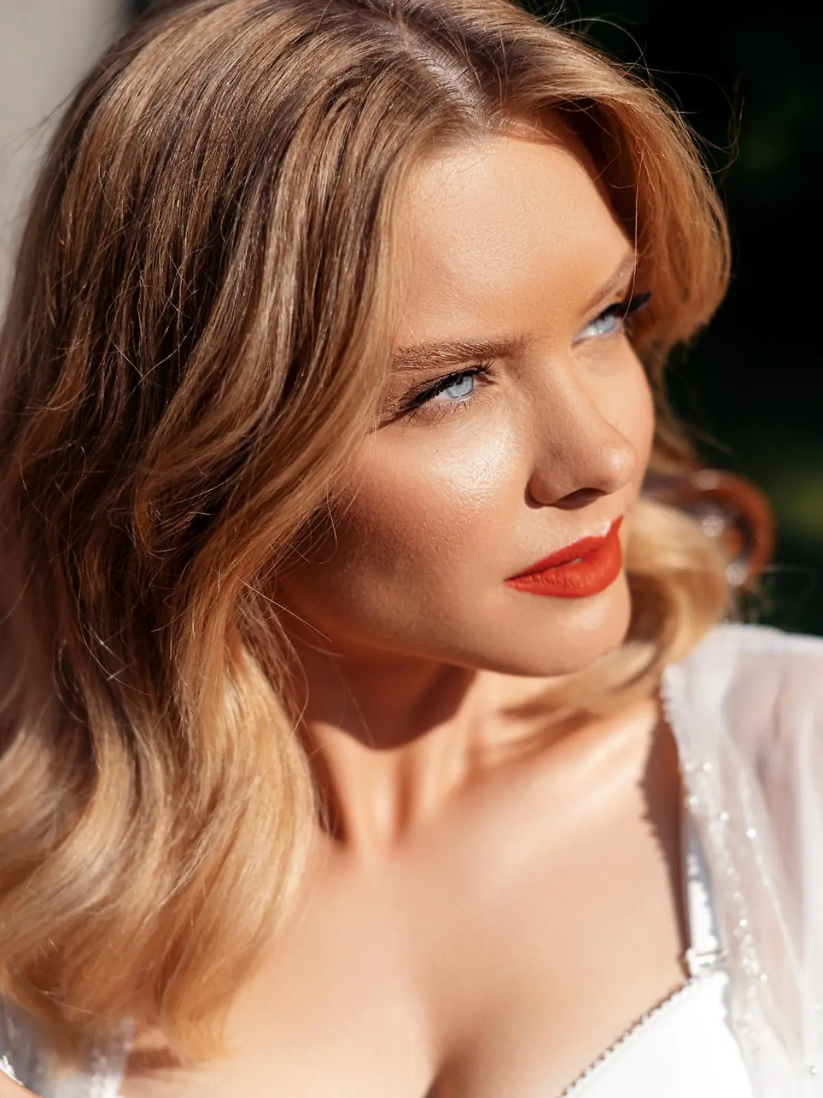 Portrait of attractive young woman with blue eyes and blond hair posing on nature. Stunning bride having wedding makeup and hairstyle. Concept of people, event and celebration.