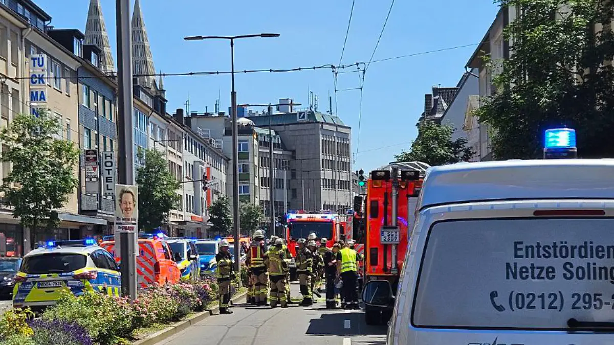 Einsatzkräfte der Feuerwehr und Polizei suchen in der Innenstadt von Solingen nach der Ursache für ein lautes Knallgeräusch und eine Rauchwolke. Eine Hauptverkehrsstraße wurde weiträumig abgesperrt.