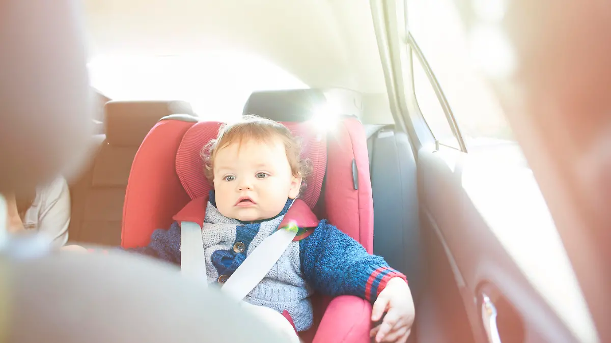 Baby boy strapped into his car seat on a journey. He is watching a dvd on the in car entertainment system.
