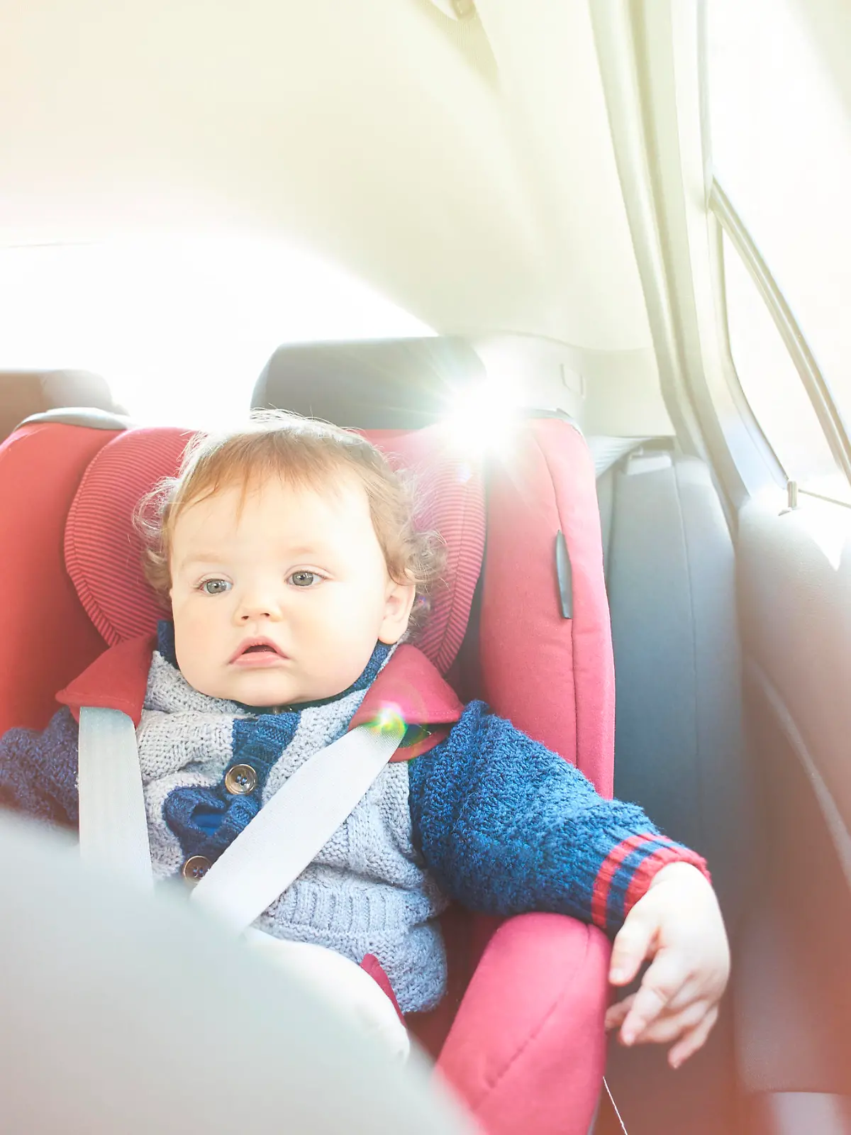 Baby boy strapped into his car seat on a journey. He is watching a dvd on the in car entertainment system.