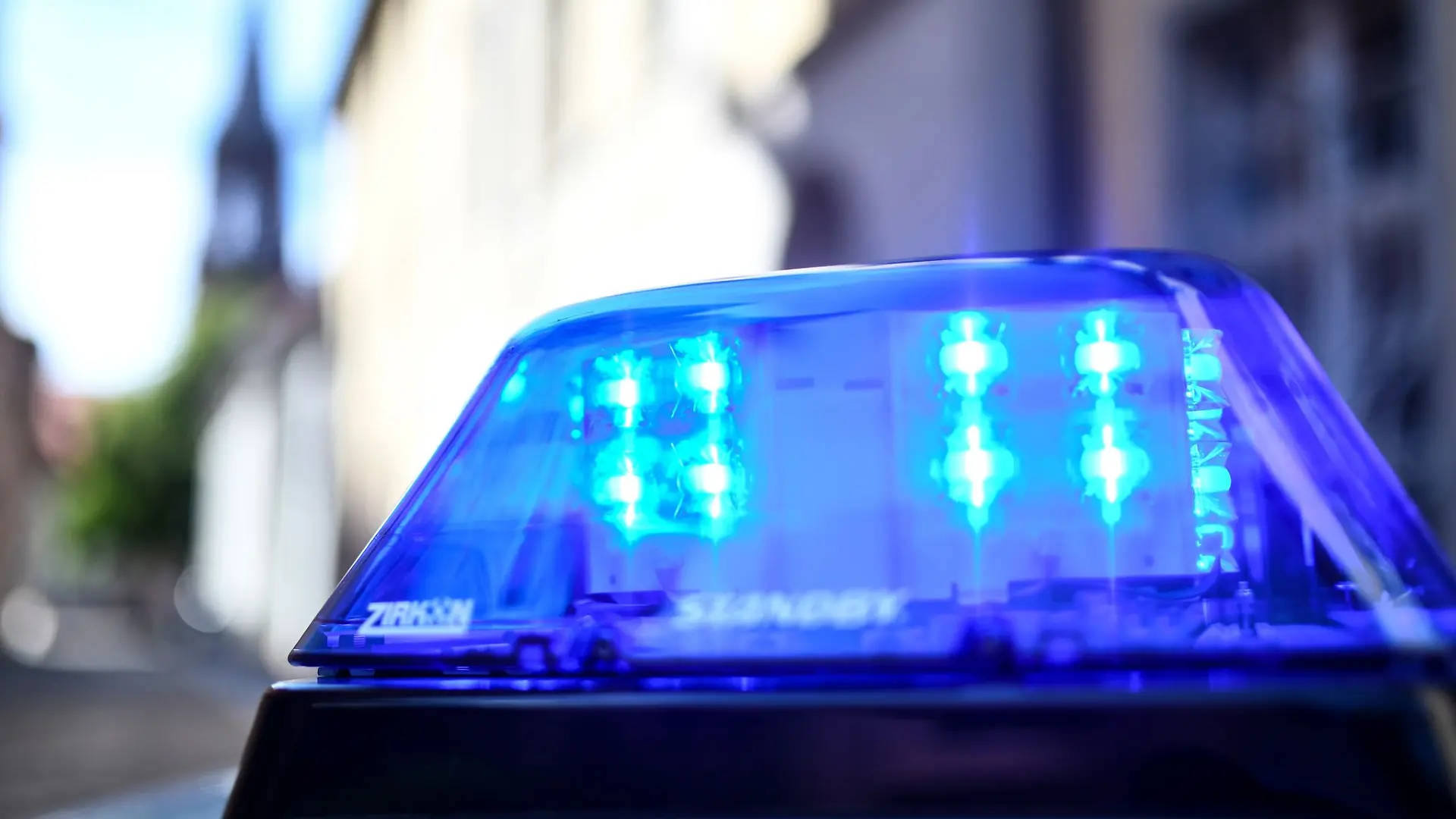 Ein Polizeiauto mit blinkendem Blaulicht steht vor einem Gebäude.