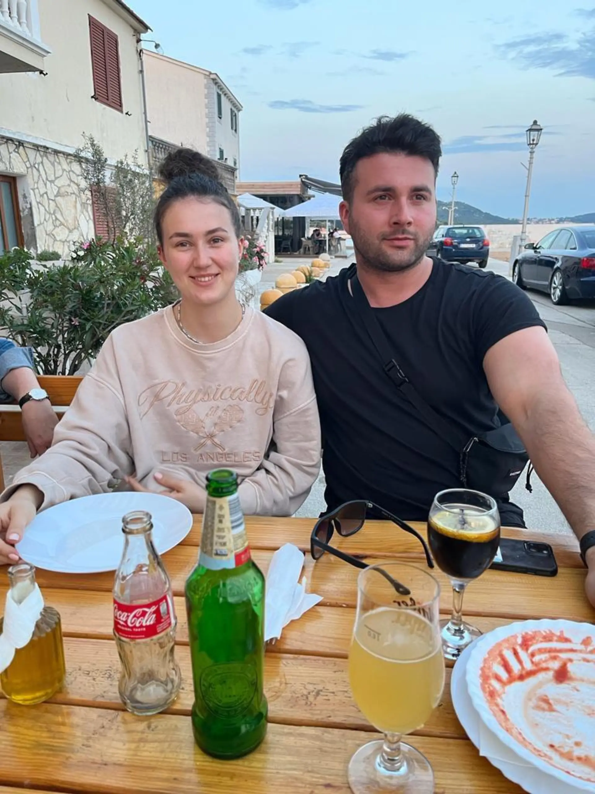 Rechts: Philipp Fischer, links: seine Schwester Elena. Die beiden sitzen nebeneinander in einem Restaurant und lächeln. 