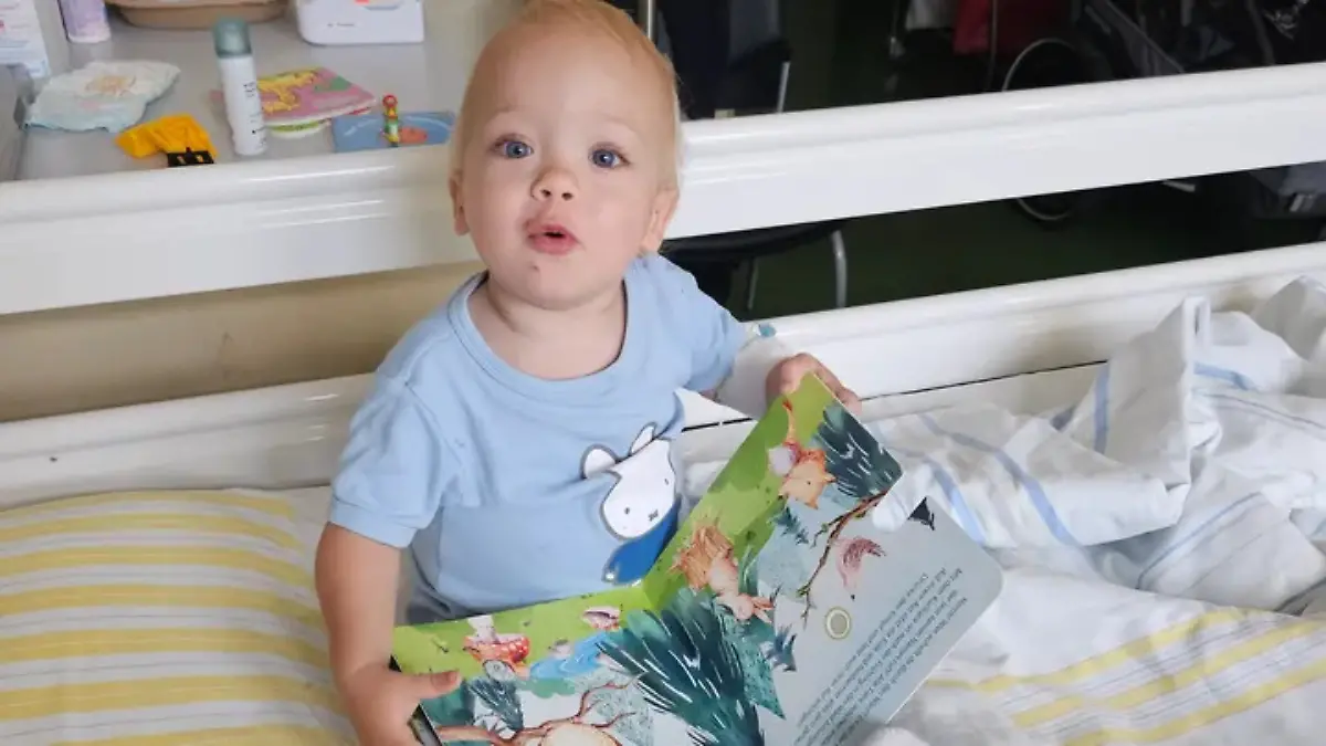 Levi sitzt auf dem Krankenhausbett und hält ein Buch in der Hand.