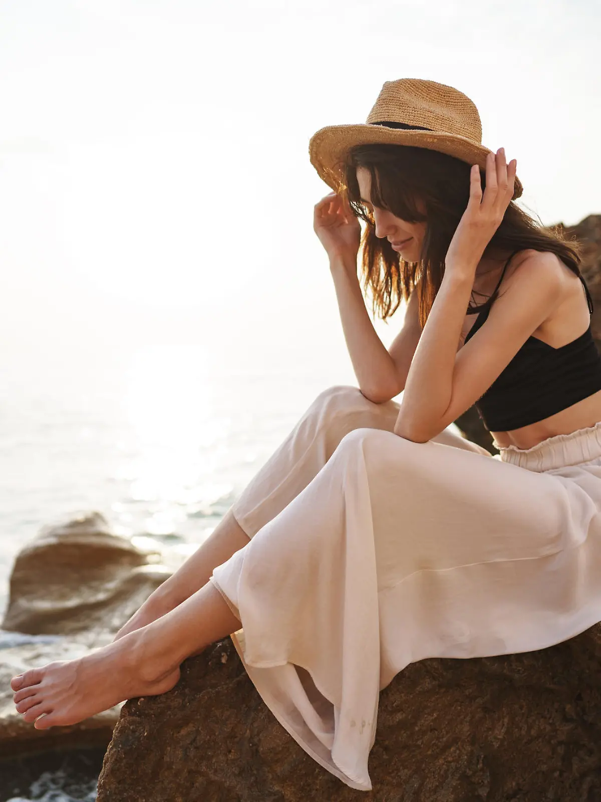 Woman traveler sitting near sea on cliff injoying view of sea and nature at summer