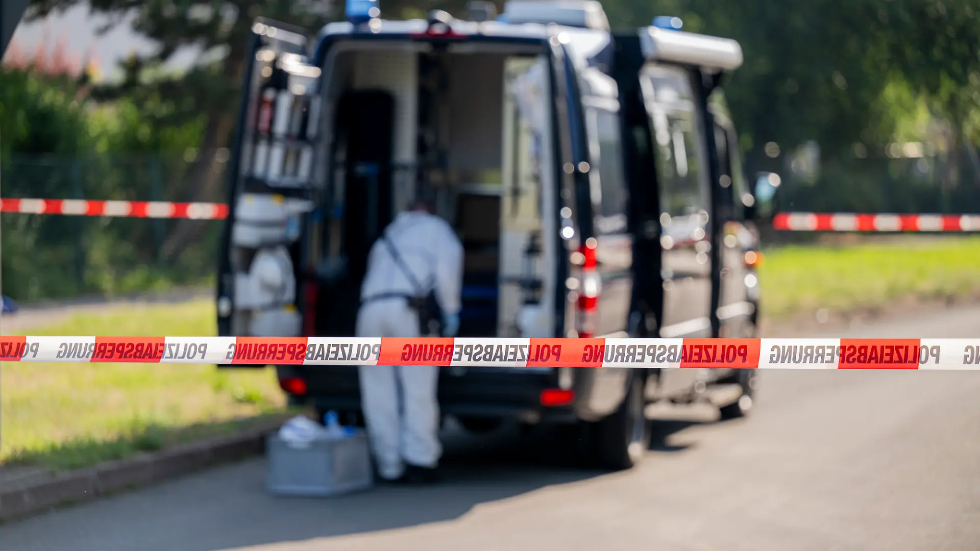 27.06.2024, Thüringen, Erfurt: Ein Mitarbeiter der Spurensicherung ist vor einem Einsatzfahrzeug zu sehen. Ein Mann wurde in Erfurt erschossen. Der Großeinsatz der Polizei läuft.