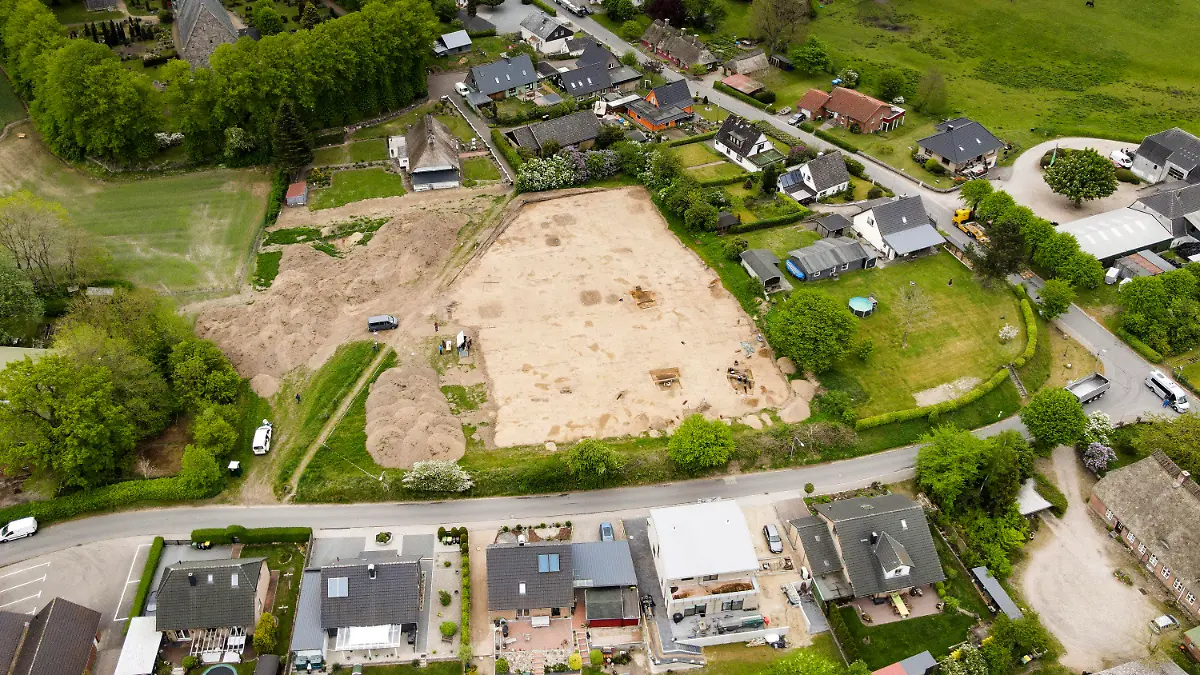 17.05.2022, Schleswig-Holstein, Süderbrarup: Ausgrabungsarbeiten werden auf einer Baustelle in einem Wohngebiet durchgeführt. Der neue wikingerzeitliche Fundplatz in Norderbrarup liegt im Ortskern in exponierter Lage nahe der über 800 Jahre alten Kirche. Er wurde im Zuge von Ausgrabungen des Archäologischen Landesamtes Schleswig-Holstein entdeckt, die im Vorfeld der Umsetzung eines hier geplanten Wohnbaugebietes durchgeführt werden. (Luftaufnahme mit Drohne) Foto: Frank Molter/dpa - ACHTUNG: Nur zur redaktionellen Verwendung im Zusammenhang mit der aktuellen Berichterstattung und nur mit vollständiger Nennung des vorstehenden Credits und Verwendung nur im vollen Format +++ dpa-Bildfunk +++