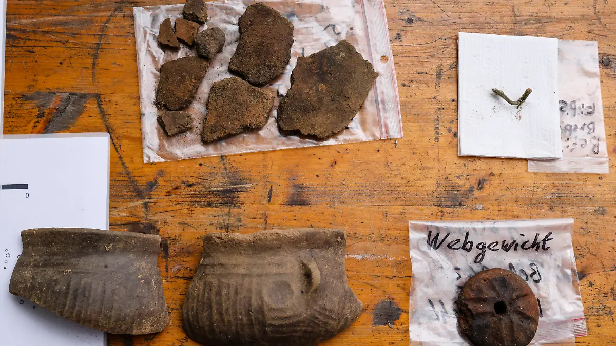 17.05.2022, Schleswig-Holstein, Süderbrarup: Fundstücke einer Ausgrabung liegen auf einem Tisch. 2021 hatte das Archäologische Landesamt Schleswig-Holstein bei einer Voruntersuchung zwischen Brebel und Süderbrarup im Kreis-Schleswig Flensburg eine Siedlung aus den Jahrhunderten um Christi Geburt entdeckt. Nun werden im Vorfeld der Erschließung eines Gewerbegebietes archäologische Befunde dokumentiert, wie zum Beispiel Teile von Haushaltskeramiken und ein Webstuhlgewicht. Foto: Frank Molter/dpa +++ dpa-Bildfunk +++