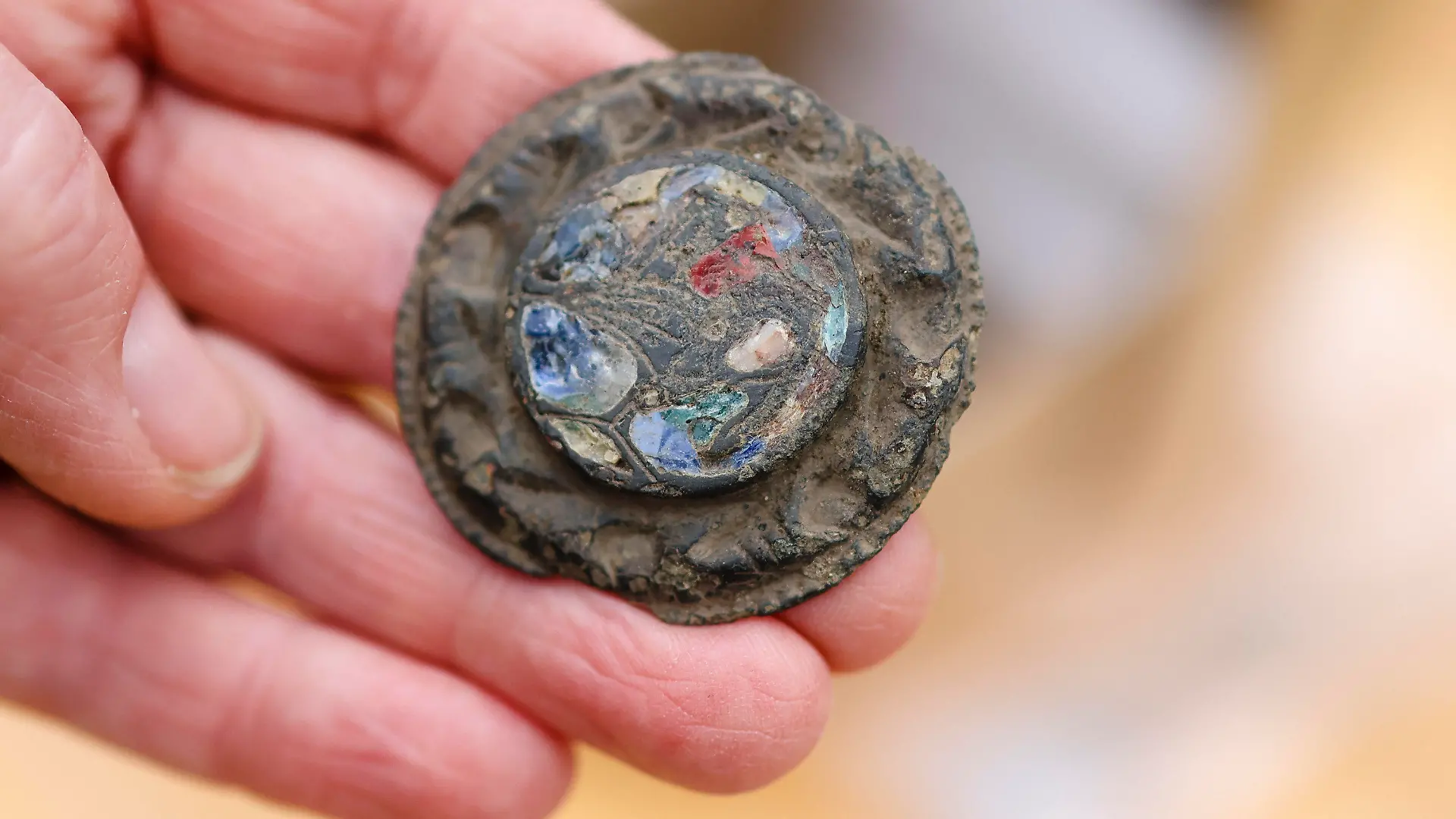 17.05.2022, Schleswig-Holstein, Süderbrarup: Eine Fibel zum Schließen eines Gewandes liegt in einer Hand. Der neue wikingerzeitliche Fundplatz in Norderbrarup liegt im Ortskern in exponierter Lage nahe der über 800 Jahre alten Kirche. Er wurde im Zuge von Ausgrabungen des Archäologischen Landesamtes Schleswig-Holstein entdeckt, die im Vorfeld der Umsetzung eines hier geplanten Wohnbaugebietes durchgeführt werden. Foto: Frank Molter/dpa +++ dpa-Bildfunk +++