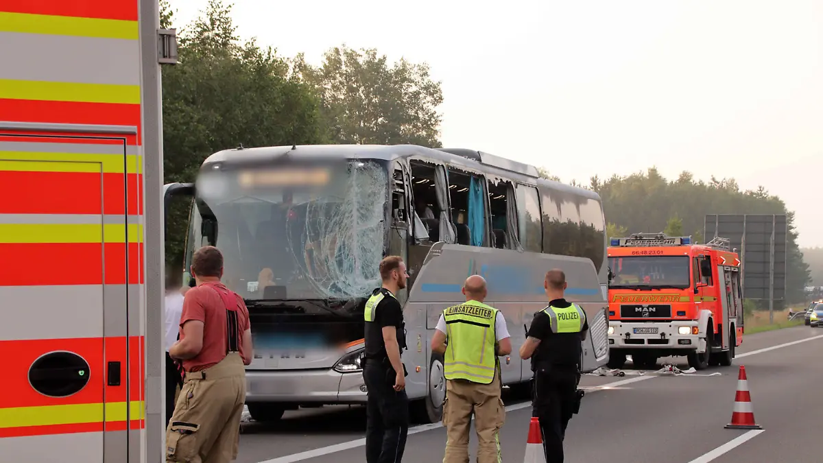 28.06.2024, Mecklenburg-Vorpommern, Blievenstorf: Rettungskräfte stehen neben einem verunfallten Reisebus auf der Autobahn 24. Der Bus aus Polen mit 59 Menschen an Bord war zwischen Hamburg und Berlin nach ersten Erkenntnissen von der Fahrbahn abgekommen. Er kollidierte mit der Mittelschutzplanke und einem Verkehrsschild, wie die Polizei mitteilte. Sämtliche Scheiben der linken Seite des Busses wurden durch den Aufprall beschädigt. 16 Reisende wurden durch Glassplitter im Gesicht verletzt.
