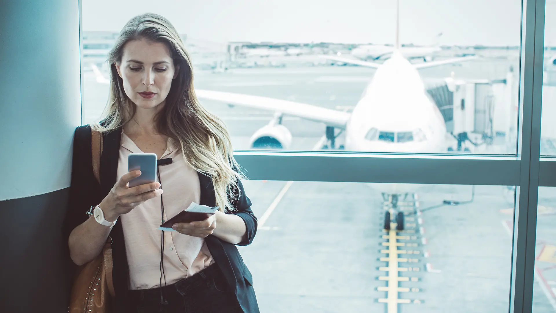 Frau wartet am Flughafen und ist mit dem Handy / Smartphone im Wlan