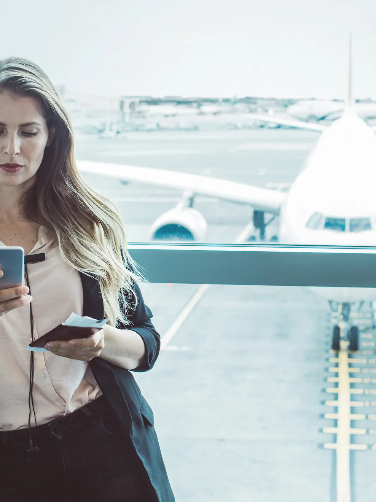 Frau wartet am Flughafen und ist mit dem Handy / Smartphone im Wlan 