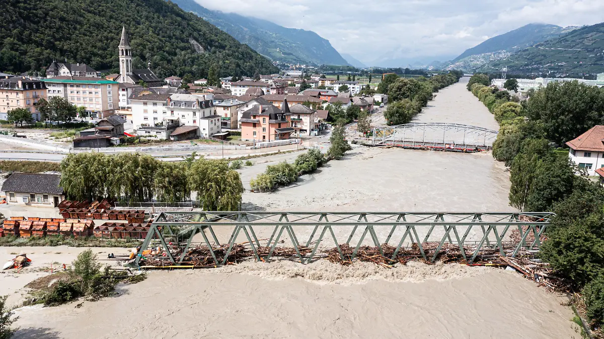 30.06.2024, Schweiz, Siders: Die Rhone (r) und der Fluss Navizence (l) sind nach Unwettern, die schwere Überschwemmungen im Kanton Wallis verursacht haben, in der Industriezone «Constellium» über die Ufer getreten. Foto: Olivier Maire/KEYSTONE/dpa +++ dpa-Bildfunk +++