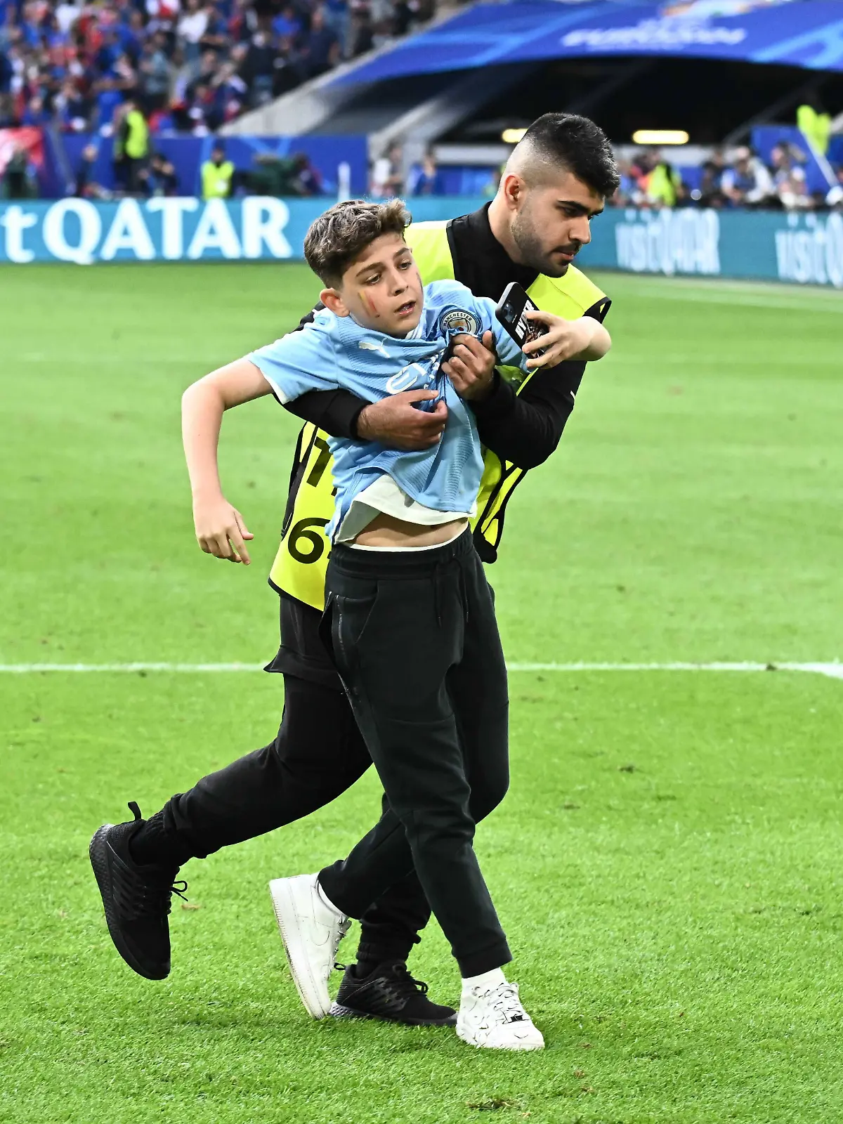 Ein Ordner zerrt einen kleinen Jungen vom Platz.