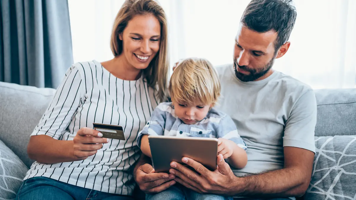 Young cheerful family shopping online at home. Happy family shopping online with credit card and digital tablet.
