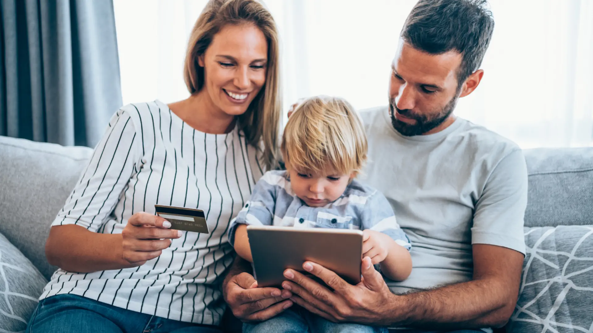 Young cheerful family shopping online at home. Happy family shopping online with credit card and digital tablet.