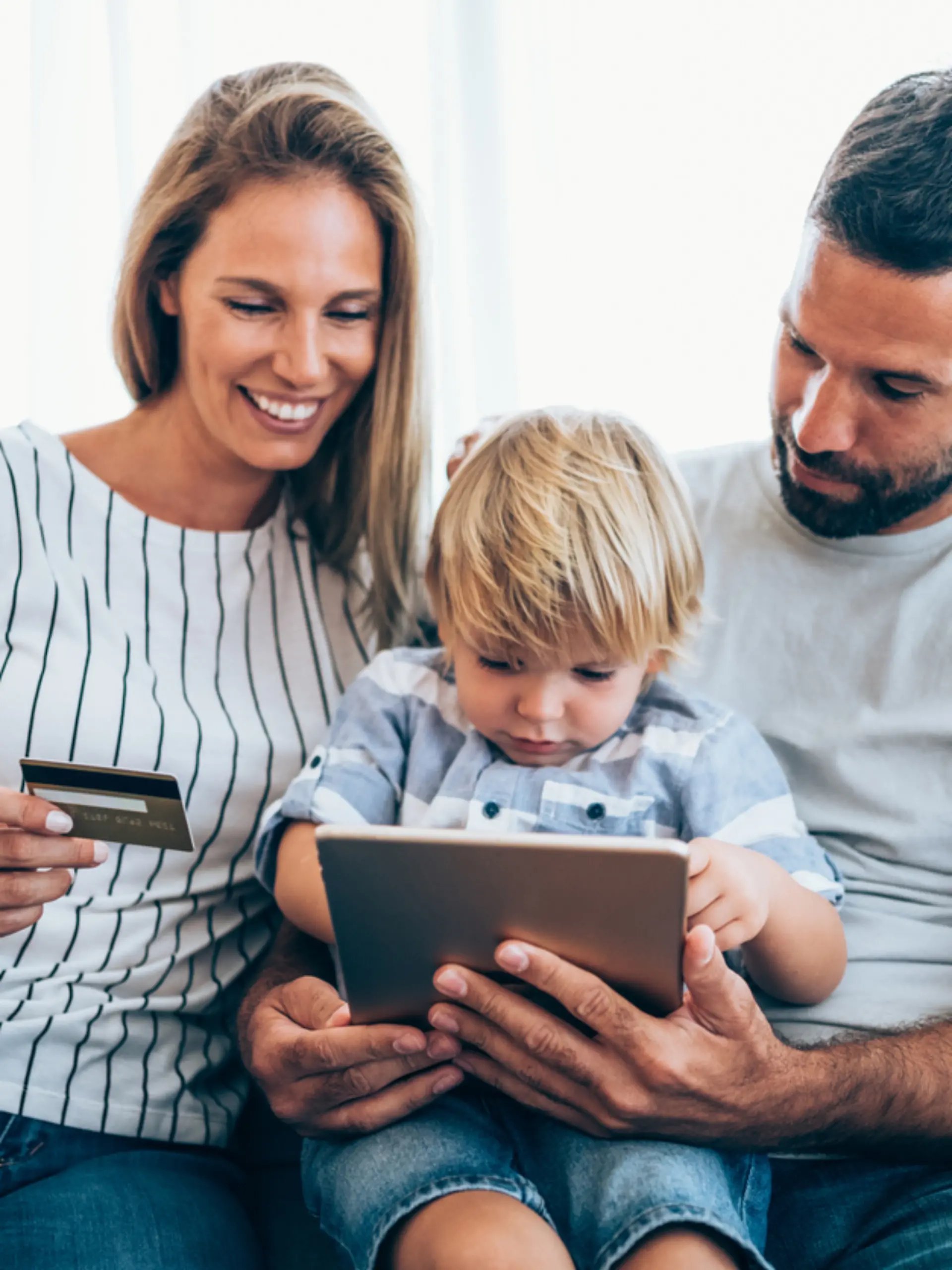 Young cheerful family shopping online at home. Happy family shopping online with credit card and digital tablet.