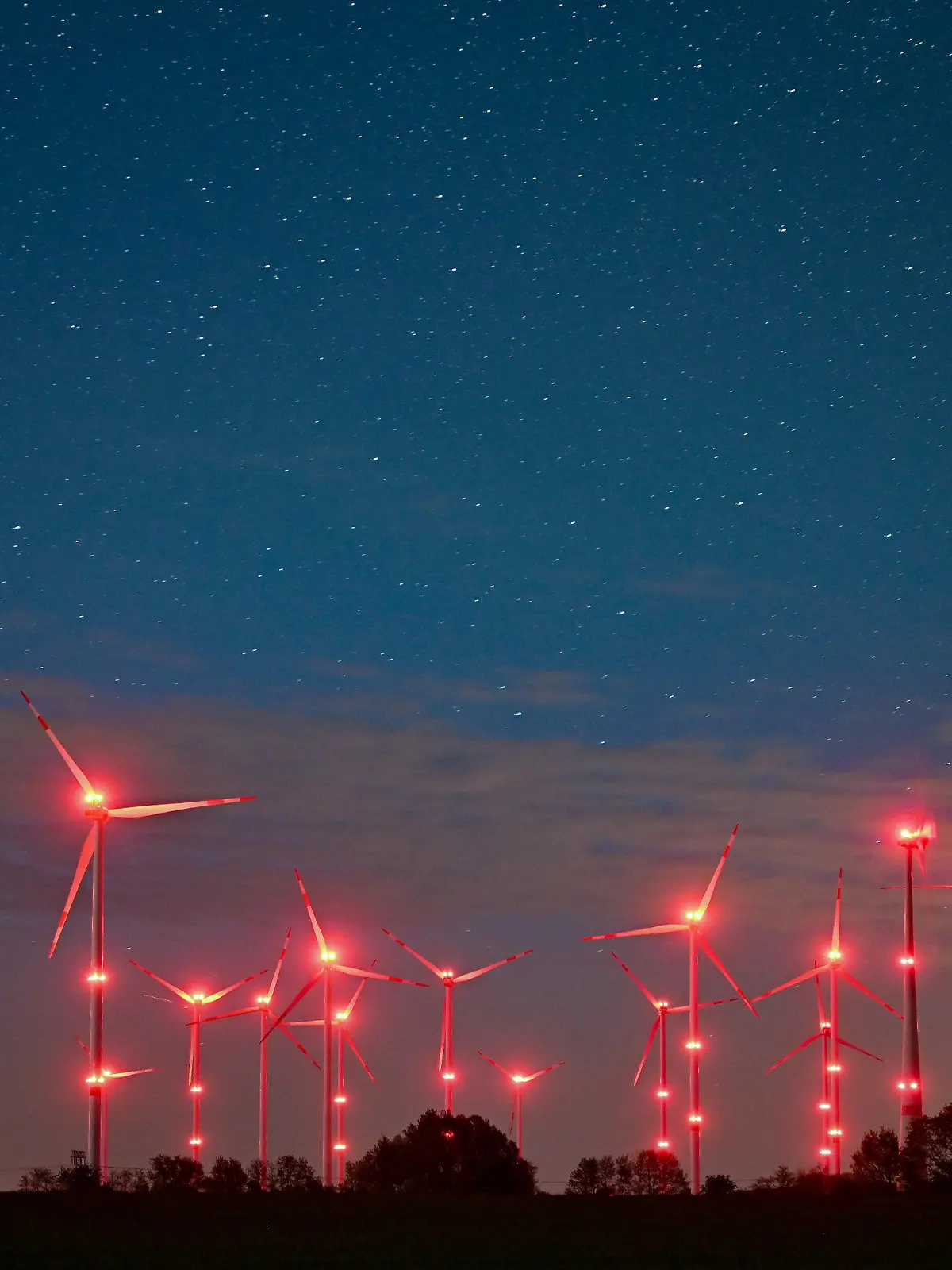 dpatopbilder - PRODUKTION - 06.05.2022, Brandenburg, Jacobsdorf: Die roten Positionslichter an Windenergieanlagen erhellen den Nachthimmel und die Landschaft. Angestrahlte Kirchen und Denkmäler, Flutlicht im Stadien und grelle Straßenbeleuchtung - die Menschen machen vielerorts die Nacht zum Tag, mit verheerenden Folgen für die Tierwelt und die Artenvielfalt. (zu dpa-KORR.: "Schattenseite des Lichts: Lichtverschmutzung wird für Tiere zur Qual") Foto: Patrick Pleul/dpa +++ dpa-Bildfunk +++