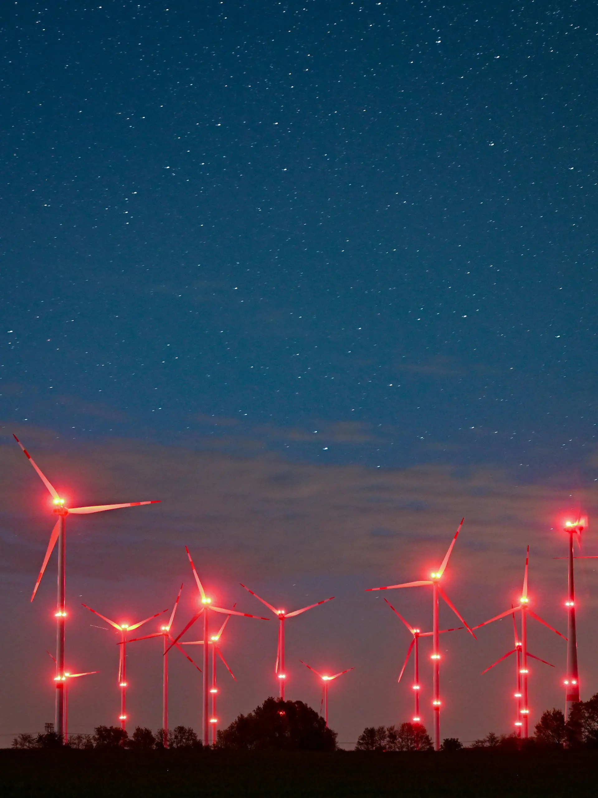 dpatopbilder - PRODUKTION - 06.05.2022, Brandenburg, Jacobsdorf: Die roten Positionslichter an Windenergieanlagen erhellen den Nachthimmel und die Landschaft. Angestrahlte Kirchen und Denkmäler, Flutlicht im Stadien und grelle Straßenbeleuchtung - die Menschen machen vielerorts die Nacht zum Tag, mit verheerenden Folgen für die Tierwelt und die Artenvielfalt. (zu dpa-KORR.: "Schattenseite des Lichts: Lichtverschmutzung wird für Tiere zur Qual") Foto: Patrick Pleul/dpa +++ dpa-Bildfunk +++