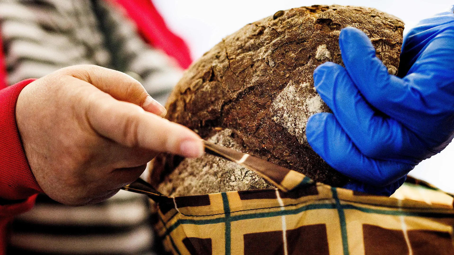 PRODUKTION - 03.07.2023, Berlin: Ein Mitarbeiter gibt ein Brot in die Tasche einer Frau an der Brotausgabe in der Ausgabestelle Paul-Schneider-Haus der Berliner Tafel. Jeden Montag findet die Ausgabe statt. Zum bevorstehenden Bundestafeltreffen kommen Vertreter der Tafeln aus ganz Deutschland zusammen, um einen neuen geschäftsführenden Vorstand der Tafel Deutschland zu wählen und diverse Themen zu diskutieren. Foto: Carsten Koall/dpa +++ dpa-Bildfunk +++