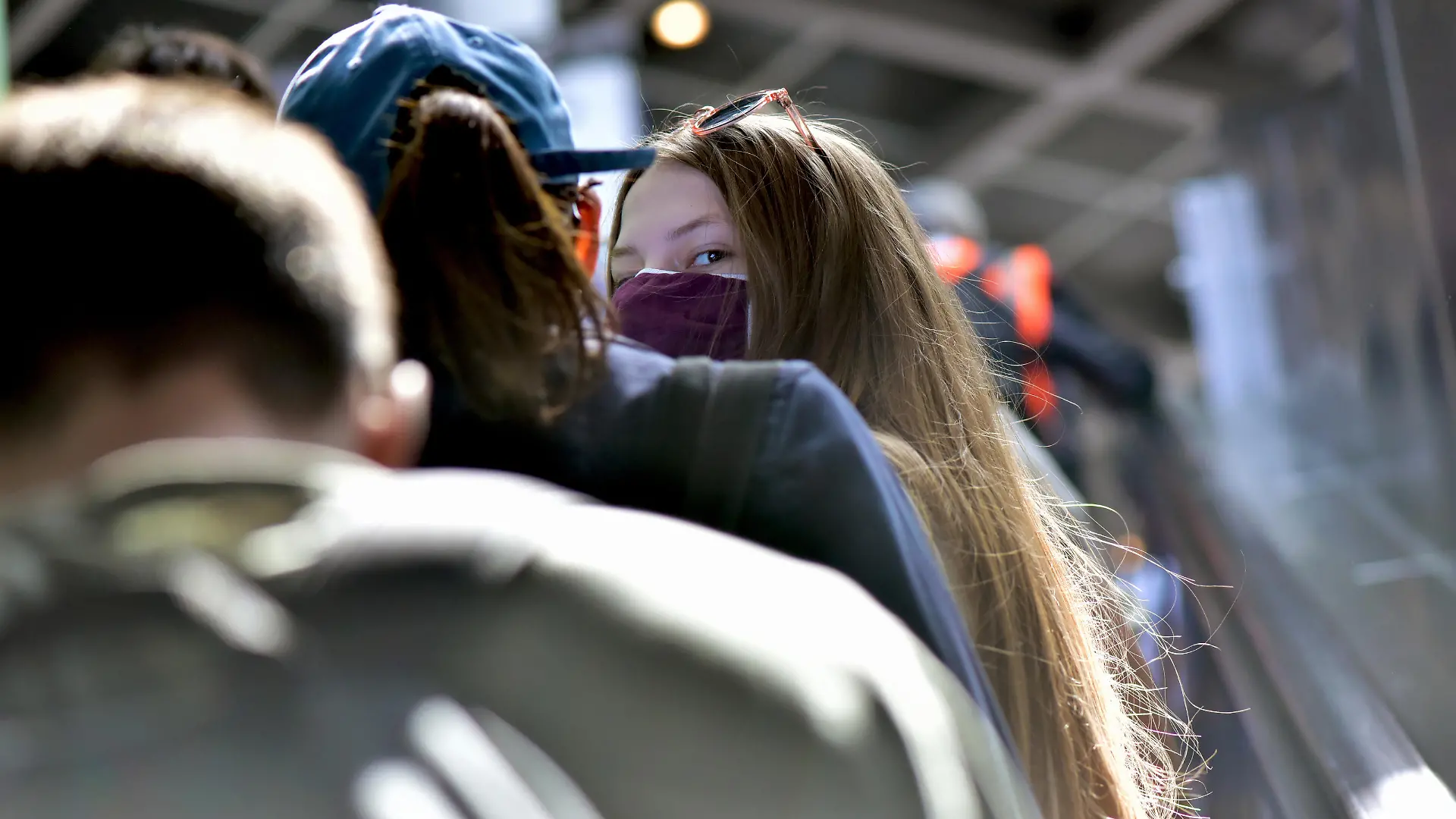 Eine junge Frau mit Mundschutz auf einer Rolltreppe im Bahnhof Südkreuz, aufgenommen am 31.05.2020. Foto: Matthias Tödt/dpa-Zentralbild/ZB