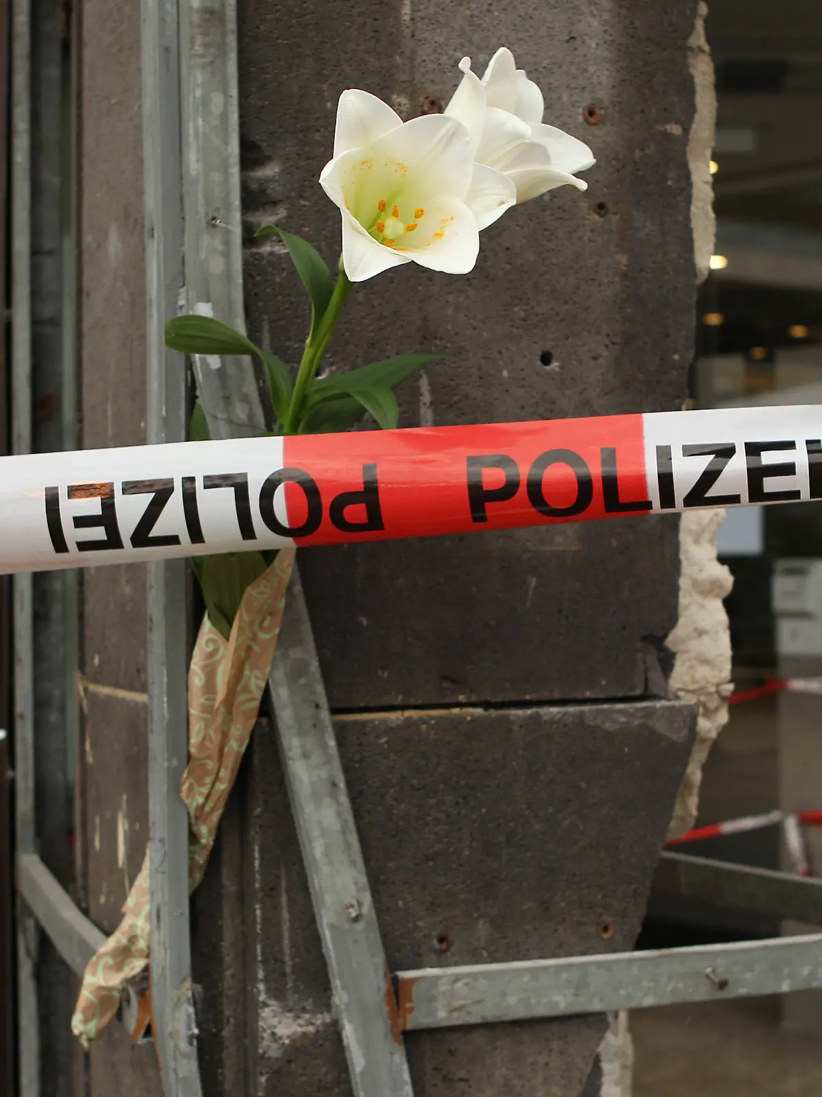 Polizeiband flattert vor der Hamburger Sparkasse am Jungfernstieg und eine Blume ist an ein Gerüstteil gesteckt worden. Am Dienstagmorgen war es vor der Filiale der Haspa in der Innenstadt zu einem schweren Autounfall gekommen. Ein 18 Jahre alte Fahrer hatte die Kontrolle über seinen Mercedes AMG verloren und war mit hoher Geschwindigkeit in ein anderes Fahrzeug gefahren. Vier Menschen wurden bei dem Unfall verletzt, ein 39-jähriger Mann erlag wenige Stunden nach dem Unfall im Krankenhaus seinen schweren Verletzungen. Altstadt Hamburg *** Police tape flutters in front of the Hamburger Sparkasse on Jungfernstieg and a flower has been pinned to a piece of scaffolding On Tuesday morning, there was a serious car accident in front of the