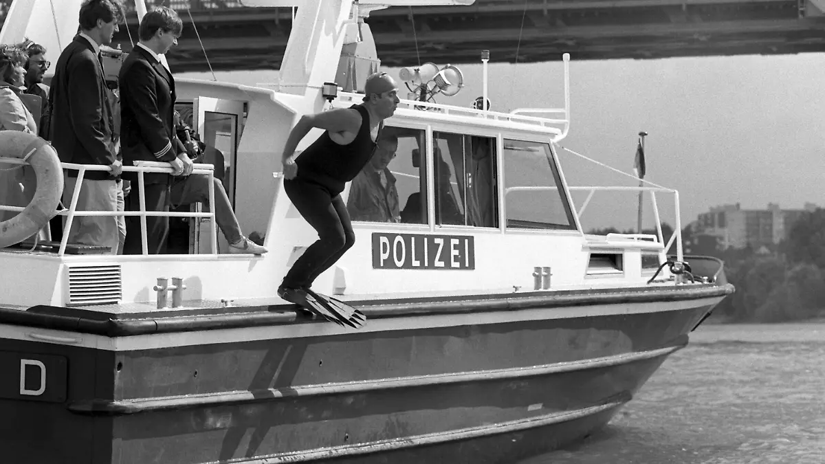Angetan mit einer Badekappe, einem Schutzanzug und Schwimmflossen springt Klaus Töpfer (50, CDU) am 13.9.1988 von Bord eines Polizeibootes in den Rhein. Der Bundesumweltminister schaffte die knapp 400 Meter lange Strecke vom hessischen Ufer zur gegenüberliegenden Seite nahe der rheinland-pfälzischen Landeshauptstadt Mainz unter Ausnutzung der kräftigen Strömung in wenigen Minuten. Begleitet wurde er von mehreren Rettungsbooten und einem Hubschrauber. Mit seiner Aktion wollte Töpfer eine persönliche Wette aus dem Jahre 1985 einlösen und keineswegs den Strom „zum Badegewässer hochstilisieren”, wie er Journalisten gegenüber deutlich machte. [dpabilderarchiv]