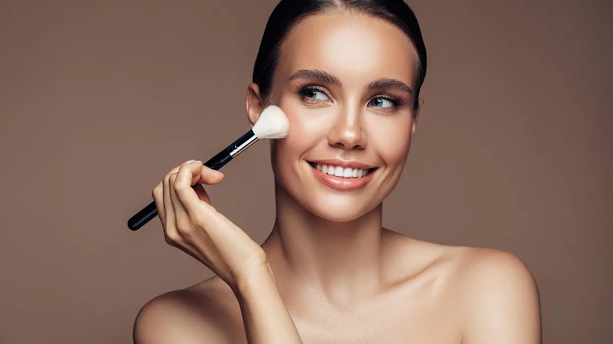 Beautiful young woman applying foundation powder