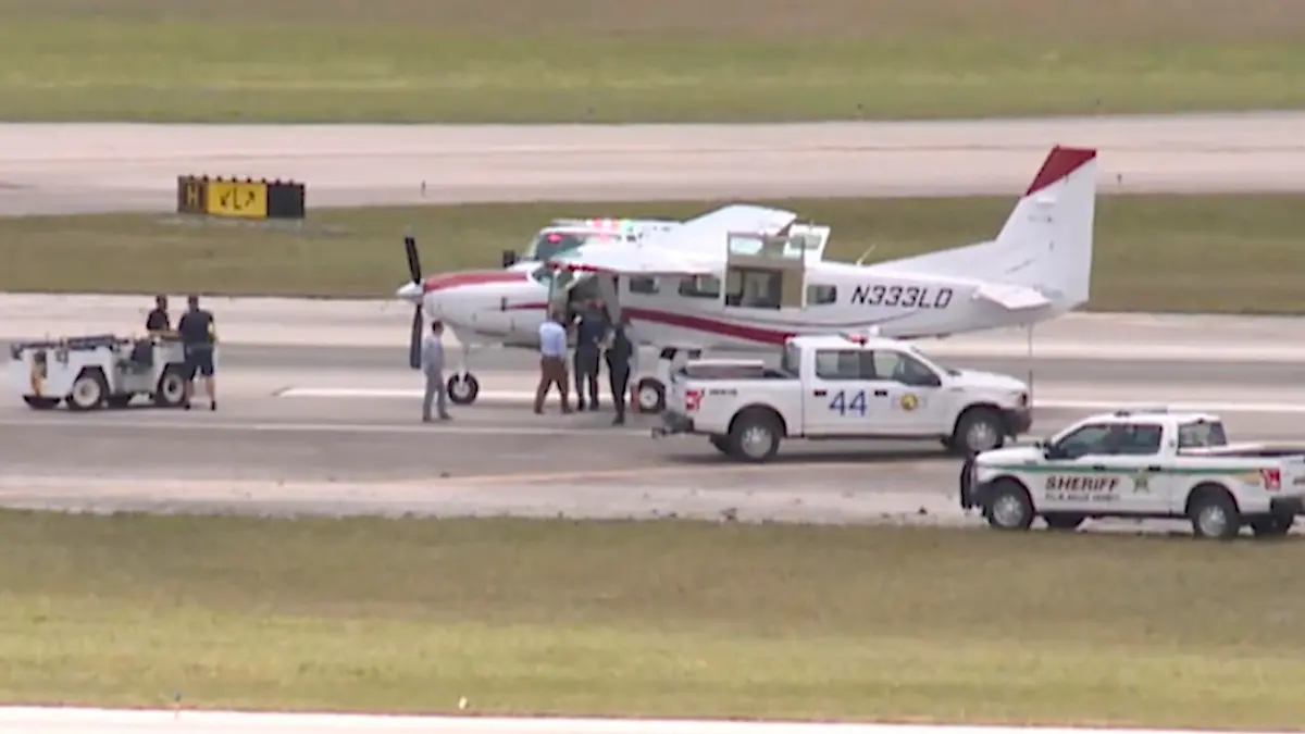 SCREENSHOT - 10.05.2022, USA, West Palm Beach: Dieses Standbild aus einem Video von WPTV zeigt Rettungskräfte, die vor einem Cessna-Flugzeug auf dem Palm Beach International Airport stehen. Ein Passagier hat nach dem Ausfall seines Piloten mit Hilfe eines Fluglotsen Medienberichten zufolge ein einmotoriges Flugzeug am Flughafen von Palm Beach im US-Bundesstaat Florida gelandet. Foto: Wptv/WPTV/AP/dpa - ACHTUNG: Nur zur redaktionellen Verwendung und nur mit vollständiger Nennung des vorstehenden Credits +++ dpa-Bildfunk +++