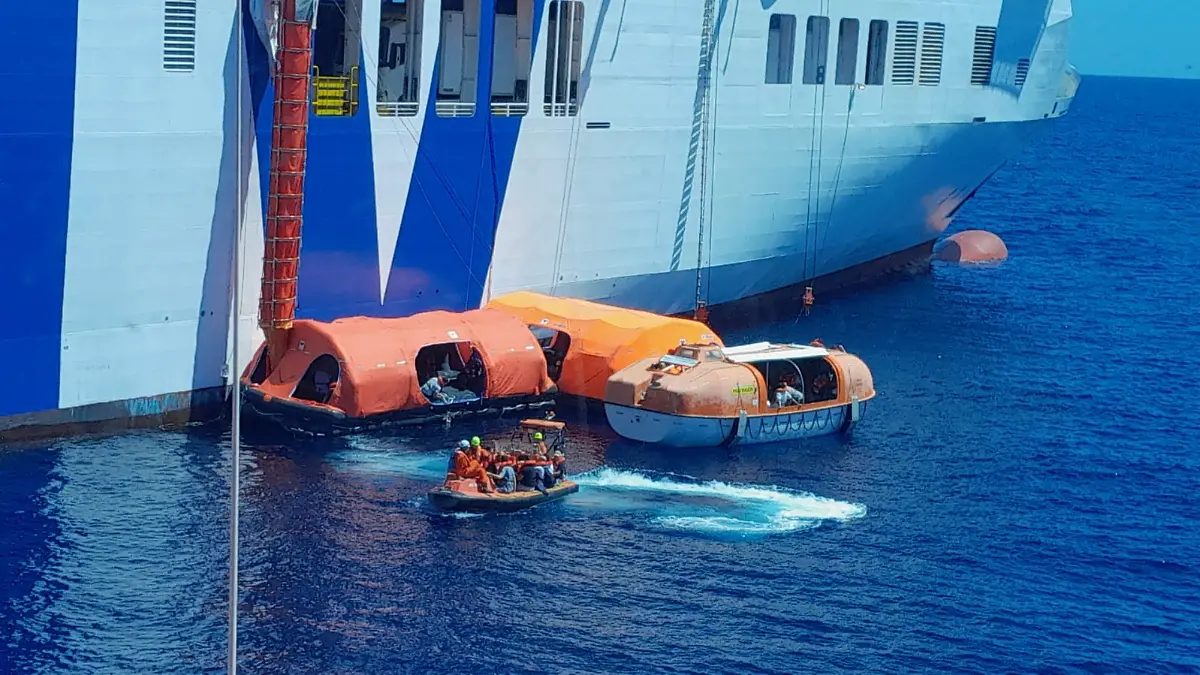 Eine Fähre auf dem Meer, daneben Rettungsboote.