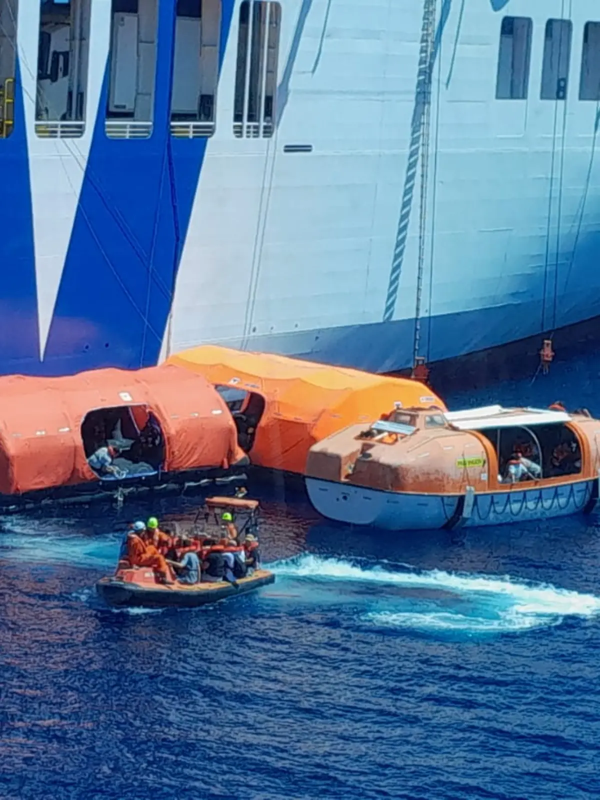 Eine Fähre auf dem Meer, daneben Rettungsboote. 