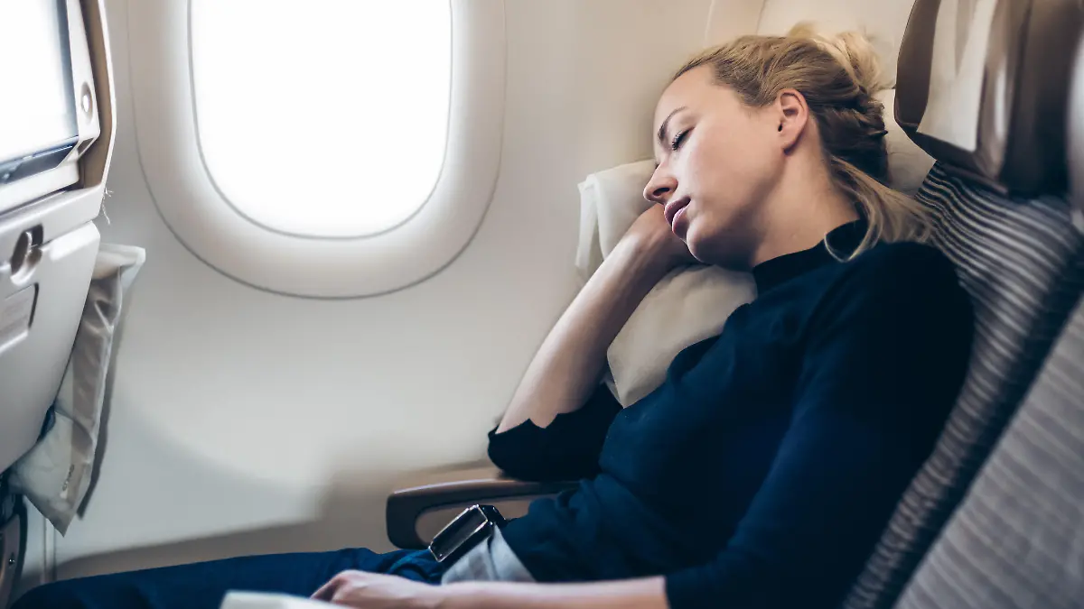 Frau lehnt sich mit geschlossenen Augen an Flugzeug-Wand an.