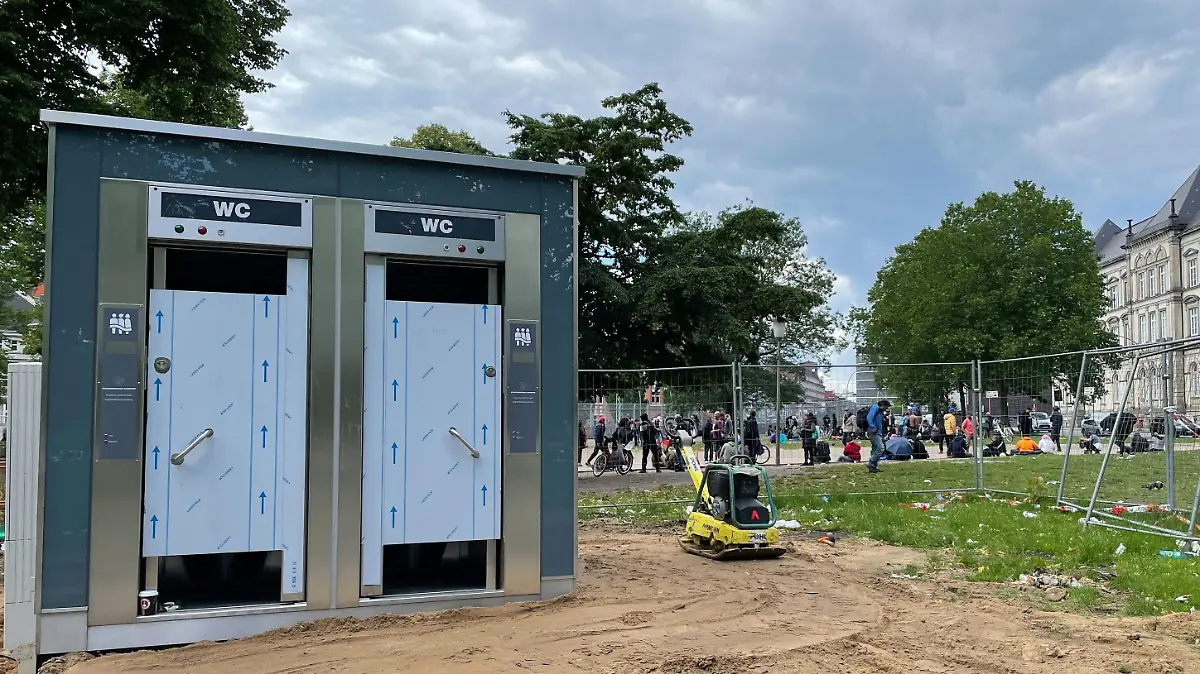 Die neuen Toiletten sind schon da. Im Hitergund sieht man, wie viele Menschen sich hier vor dem Drop Inn aufhalten.