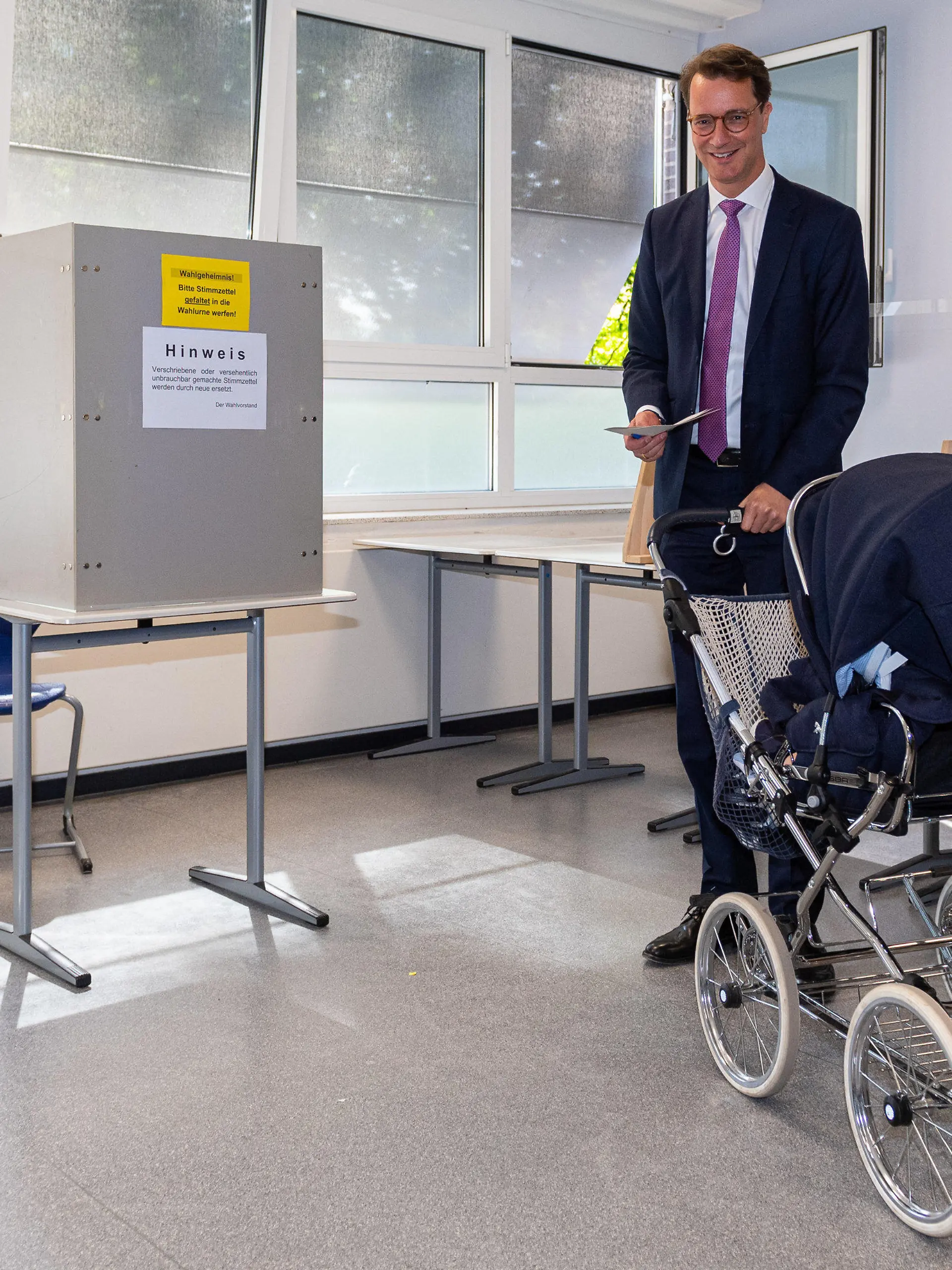 dpatopbilder - 15.05.2022, Nordrhein-Westfalen, Rhede: Hendrik Wüst (CDU), Ministerpräsident des Landes Nordrhein-Westfalen, steht zusammen mit dem Kinderwagen seiner Tochter Philippa im Wahllokal und gibt seinen Stimmzettel ab. In Nordrhein-Westfalen findet am Sonntag die Wahl zum 18. Landtag statt. Rund 13,2 Millionen Menschen sind zur Wahl aufgerufen. Foto: Guido Kirchner/dpa +++ dpa-Bildfunk +++