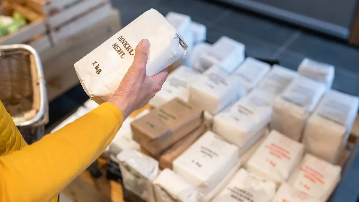 Eine Frau hält eine Packung Mehl in der Hand.
