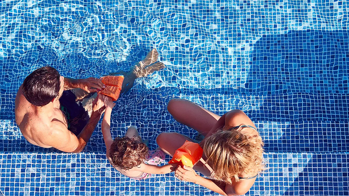 Eltern ziehen ihrem Kind Schwimmflügel an.