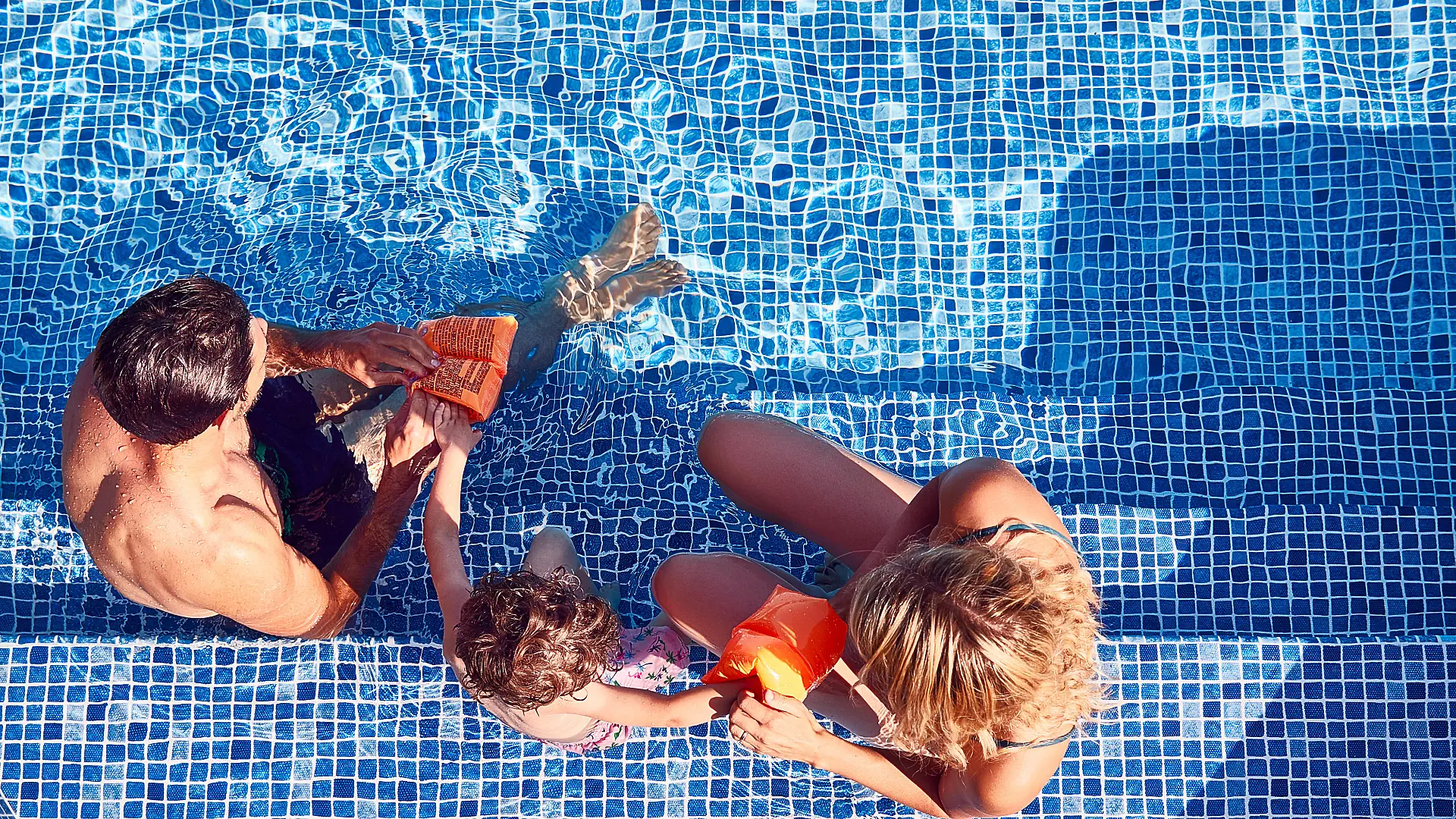 Eltern ziehen ihrem Kind Schwimmflügel an.