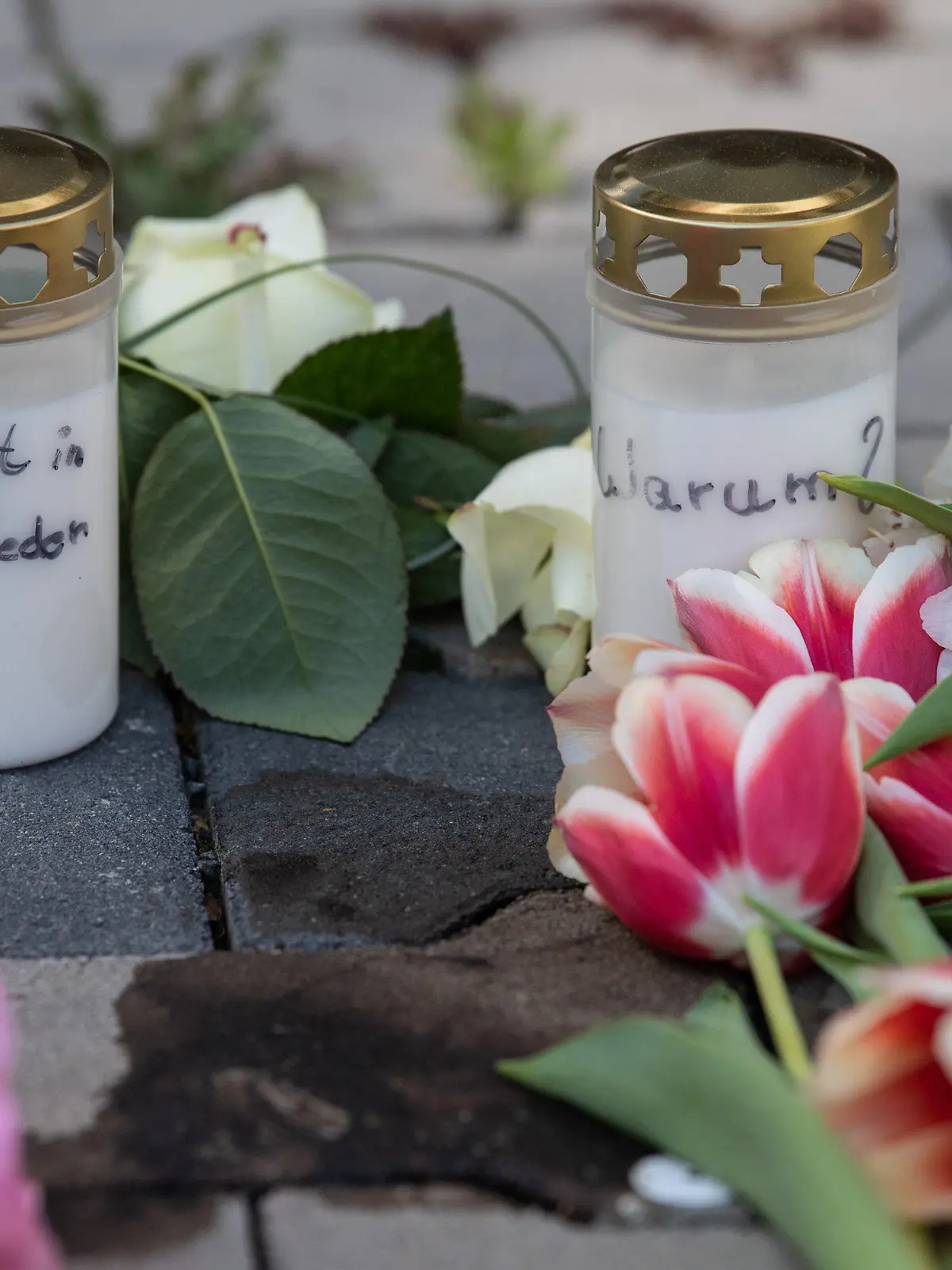 11.05.2022, Hessen, Hanau: Kerzen und Blumen erinnern nach dem gewaltsamen Tod zweier Kinder auf dem Innenhof eines Hochhauses in Hanau an die Opfer. Während die genauen Hintergründe der Tat noch unklar sind, geht die Polizei von einem familiären Hintergrund aus und fahndet nach einem Tatverdächtigen. Foto: Boris Roessler/dpa +++ dpa-Bildfunk +++