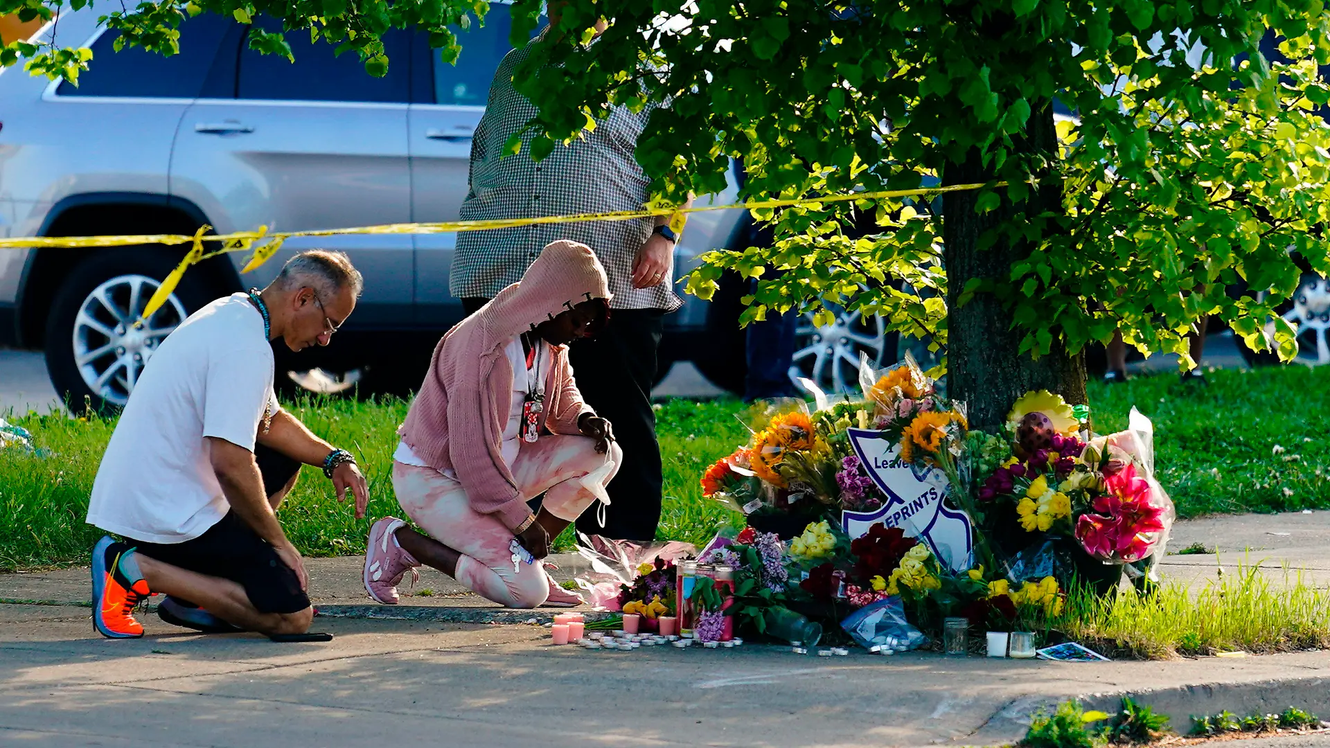 15.05.2022, USA, Buffalo: Menschen knien vor Blumen, um den Opfern tödlicher Schüsse in einem Supermarkt in Buffalo die letzte Ehre zu erweisen. Ein Schütze hatte am Samstag (14.05.2022) in der Stadt Buffalo im Bundesstaat New York das Feuer eröffnet und mindestens zehn Menschen getötet. Die demokratische Vorsitzende des US-Repräsentantenhauses Pelosi hat die Schüsse in der Stadt Buffalo als «Inlandsterrorismus» bezeichnet. Foto: Matt Rourke/AP/dpa +++ dpa-Bildfunk +++