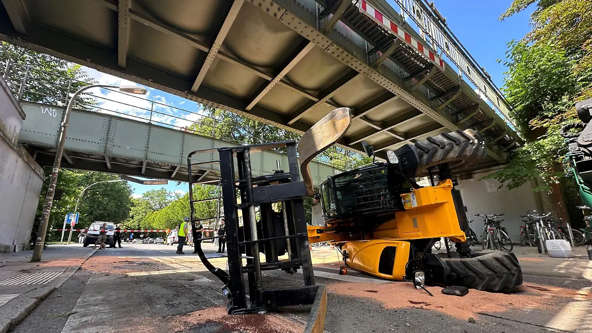 11.07.2024, Hamburg: Ein Hublader liegt umgekippt auf einer Straße in Hamburg. Ein Sattelzug hatte die Maschine transportiert. Der Hublader prallte gegen eine U-Bahn-Brücke. Die Brücke muss repariert werden, Bahnen fahren nicht. Foto: Steven Hutchings/dpa +++ dpa-Bildfunk +++