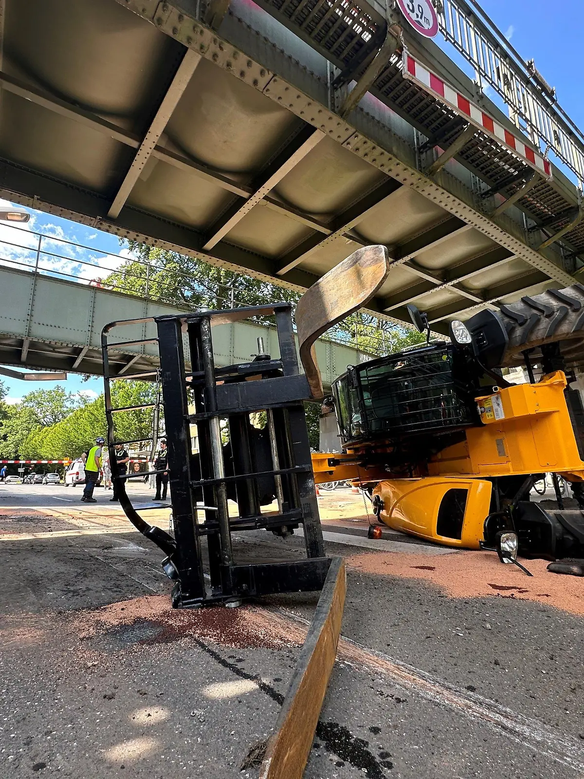 11.07.2024, Hamburg: Ein Hublader liegt umgekippt auf einer Straße in Hamburg. Ein Sattelzug hatte die Maschine transportiert. Der Hublader prallte gegen eine U-Bahn-Brücke. Die Brücke muss repariert werden, Bahnen fahren nicht. Foto: Steven Hutchings/dpa +++ dpa-Bildfunk +++