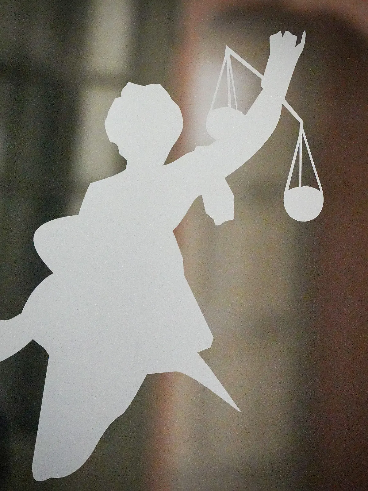 ARCHIV - 27.04.2023, Berlin: Die Figur der Justitia mit Richtschwert und Waage ist auf dem Glasfenster einer Tür im Gerichtsgebäude zu sehen. Nach dem Willen der EU-Staaten sollen Journalisten und Menschenrechtsaktivisten stärker gegen ungerechtfertigte Klagen geschützt werden. Foto: Soeren Stache/dpa +++ dpa-Bildfunk +++