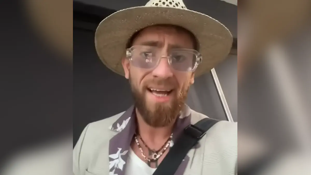 Ein Mann mit Hut und Brille blickt in die Kamera. 