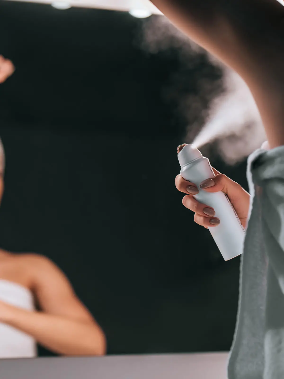 Attractive young woman in bathroom after shower is standing in front of mirror with deodorant in hands. Women care.