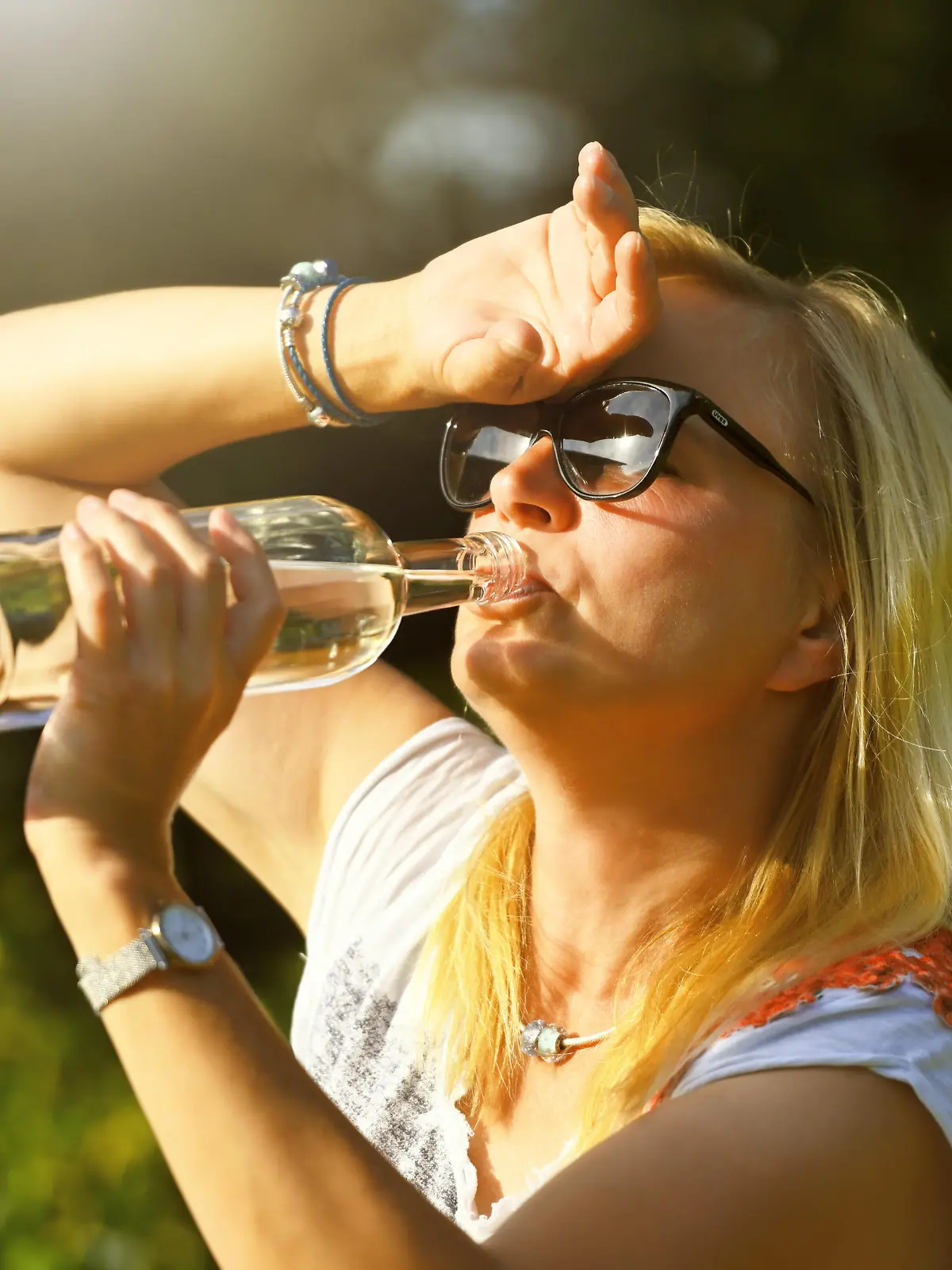 Frau im Garten trinkt Wasser aus einer Flasche, Symbolfoto Hitzewelle || Modellfreigabe vorhanden
