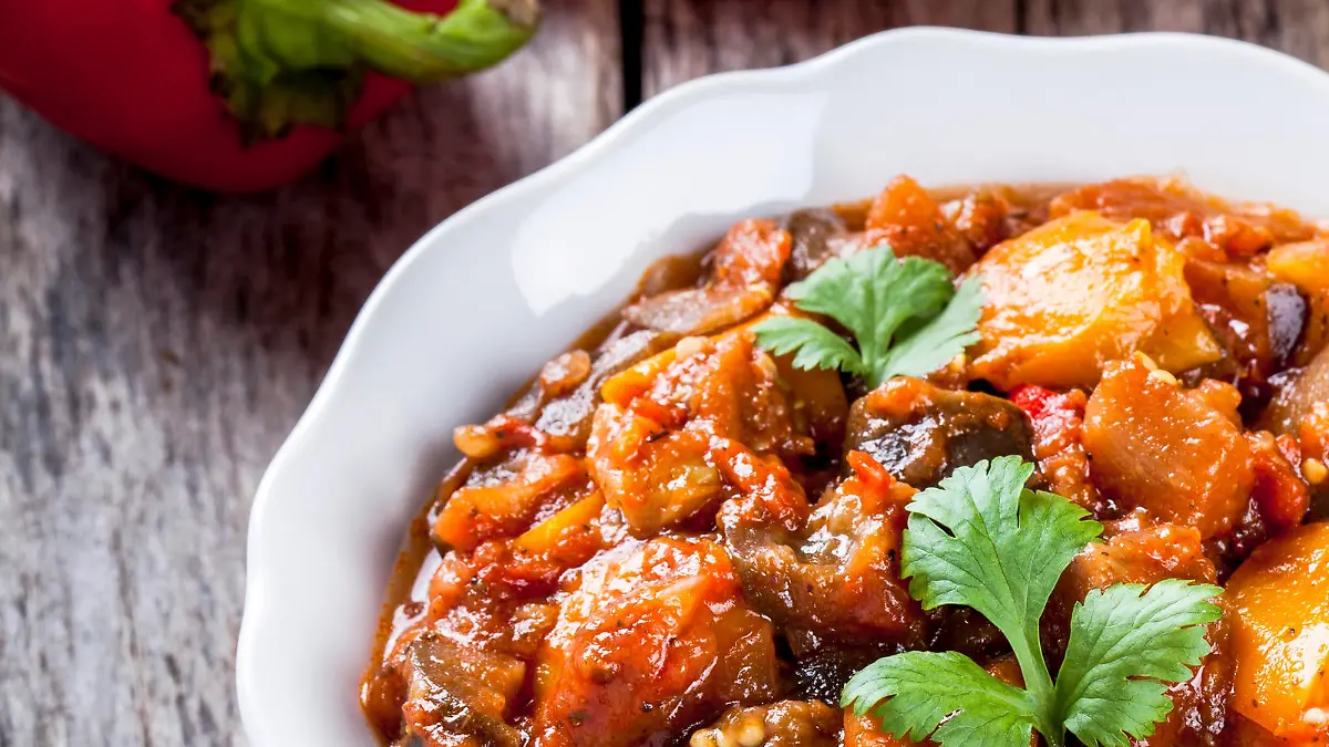 Stewed vegetables in a white bowl on wooden table