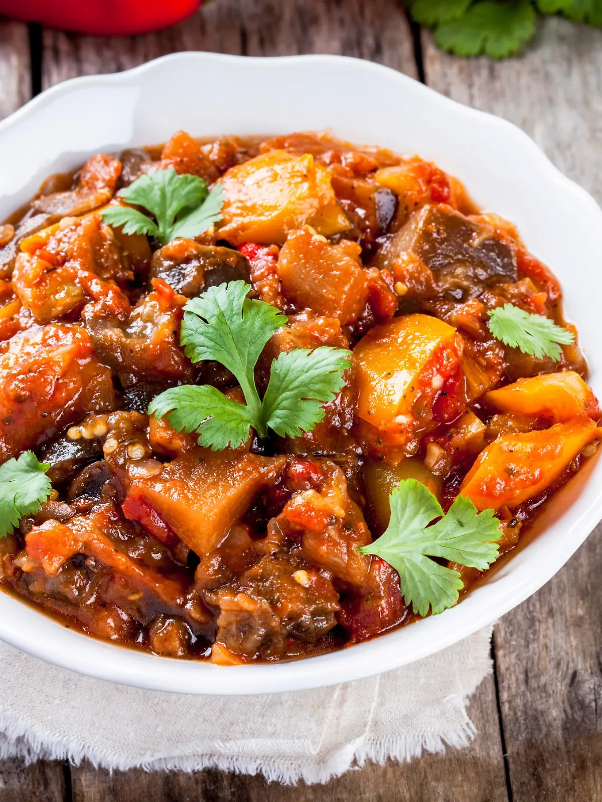 Stewed vegetables in a white bowl on wooden table